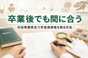 成績証明書のような書類と博物館学のテキストが並ぶ机に、科目等履修生で学芸員資格を取る方法を紹介する記事タイトル